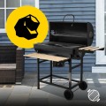 Czarny grill węglowy ogrodowy typu beczka z otwartą pokrywą i rozłożonymi drewnianymi półkami, termometrem i cyrkulacją powietrza.